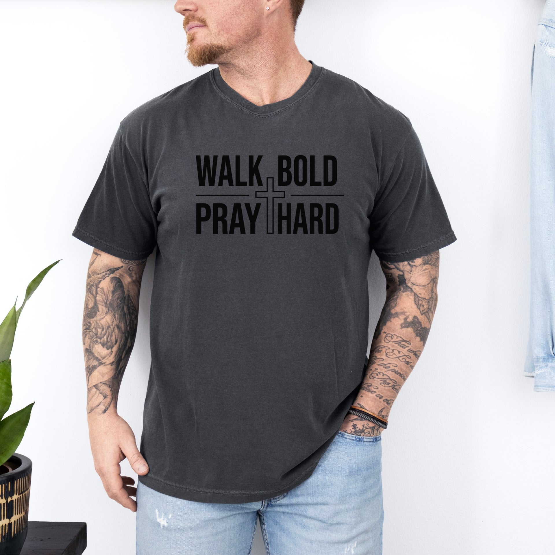 A man wearing a Walk Bold Pray Hard Christian cross t shirt, showcasing a bold design and relaxed fit.