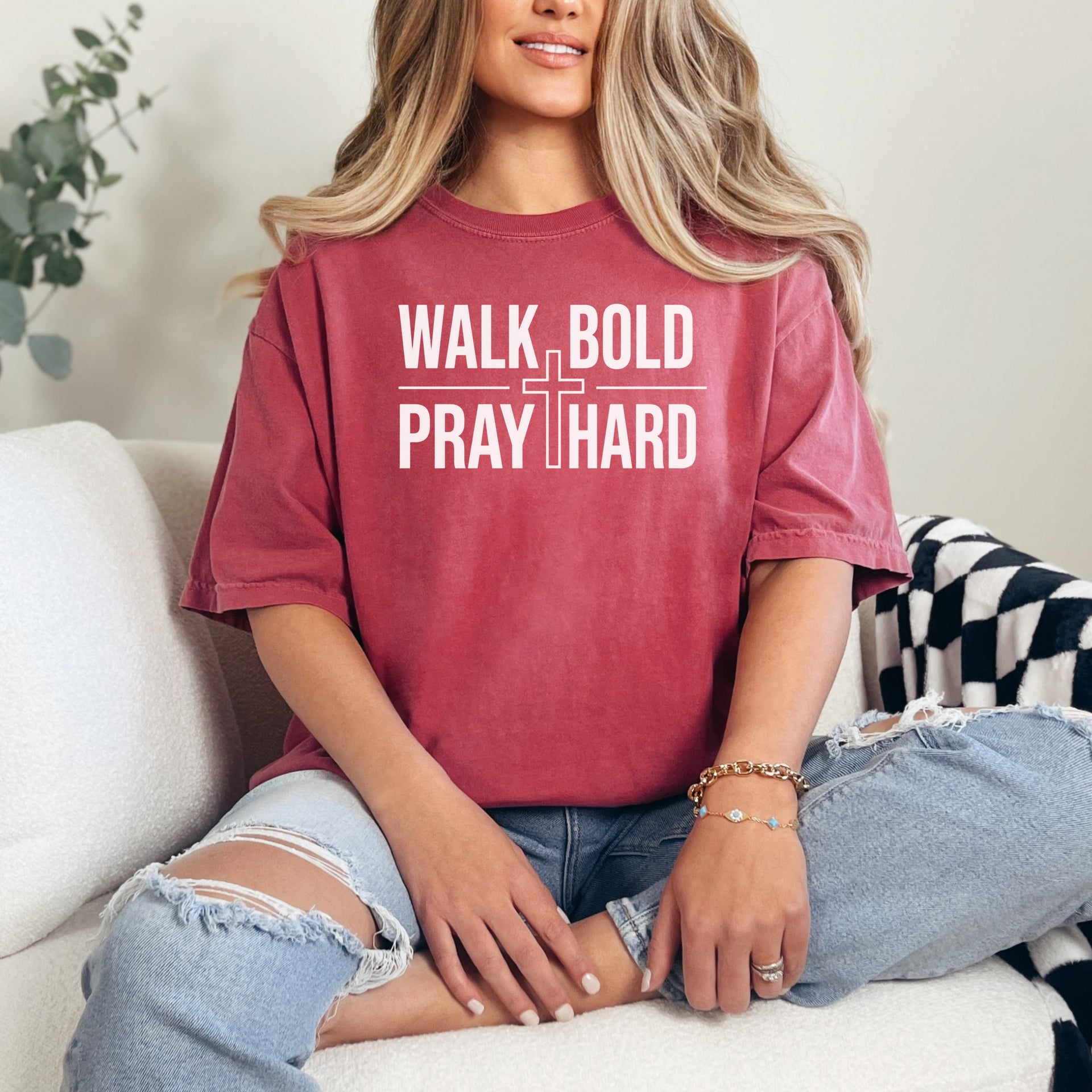 Woman wearing a Walk Bold Pray Hard Christian cross t shirt, seated comfortably, showcasing a relaxed fit and bold design.
