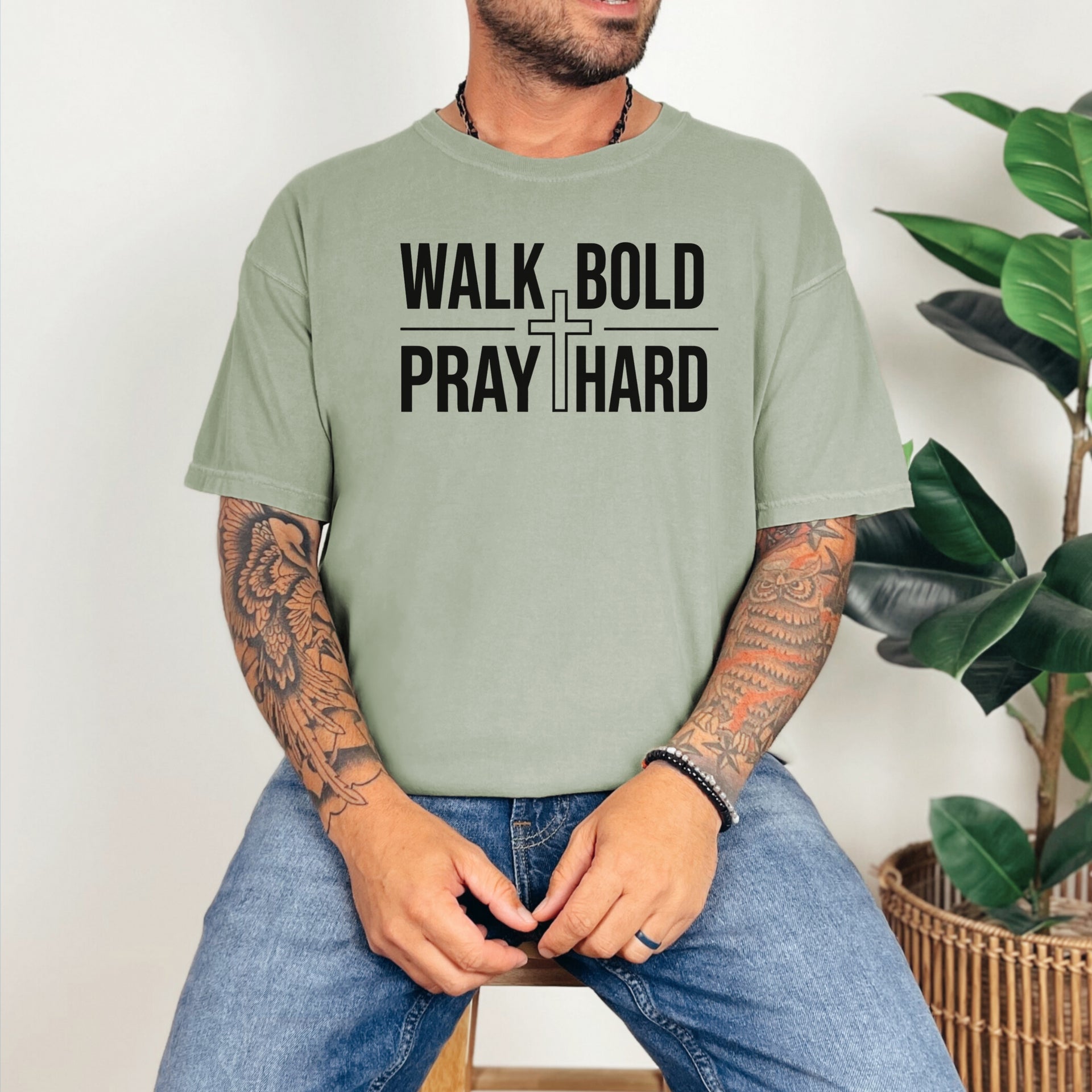 Man wearing a Walk Bold Pray Hard Christian cross t shirt in soft green, showcasing a bold faith-inspired design.