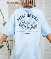 Peace Be Still T Shirt featuring waves and a cross design, perfect for conveying calm and comfort.
