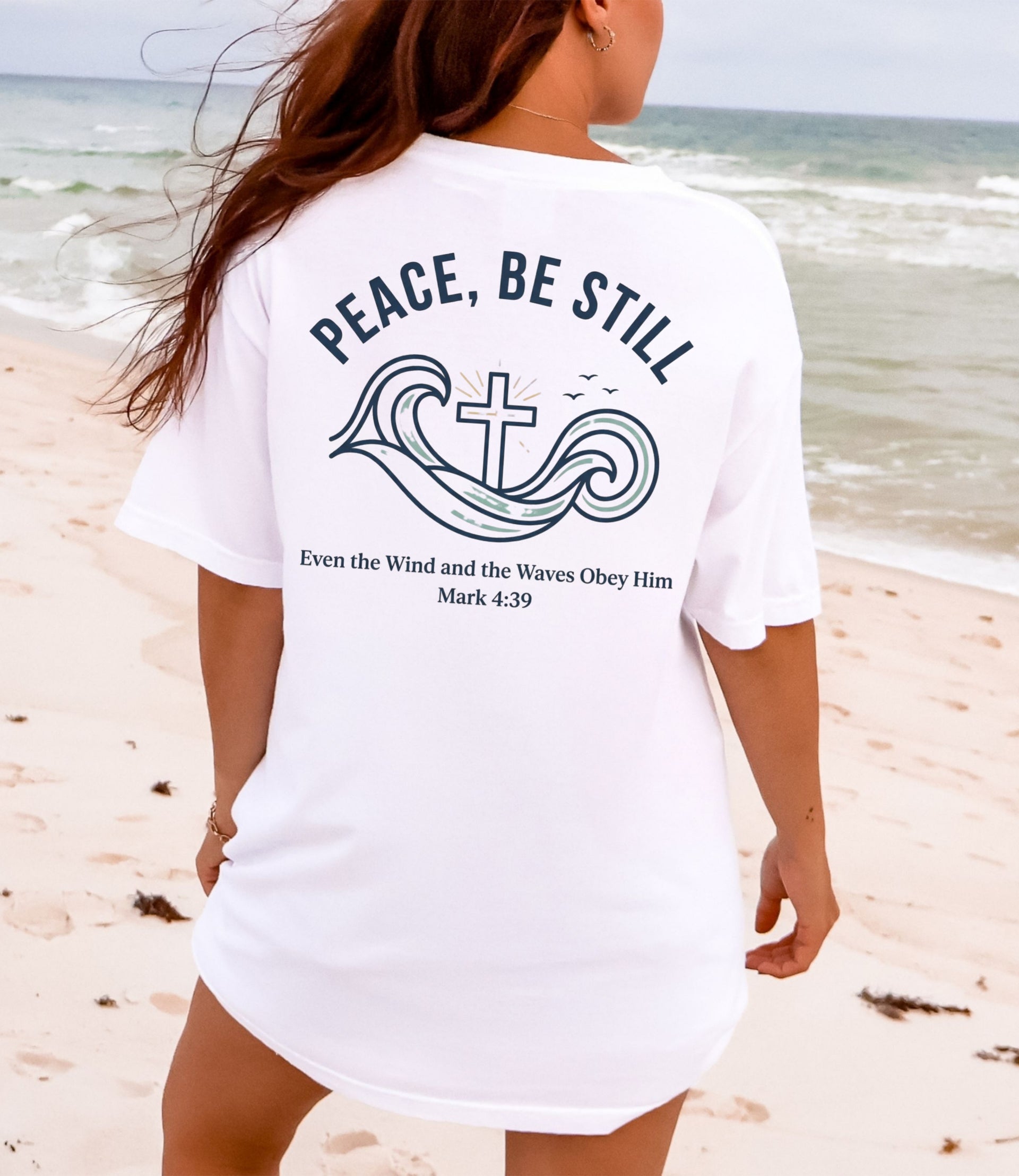 Peace Be Still T Shirt design featuring waves and cross on a woman at the beach, promoting calm and trust in God.