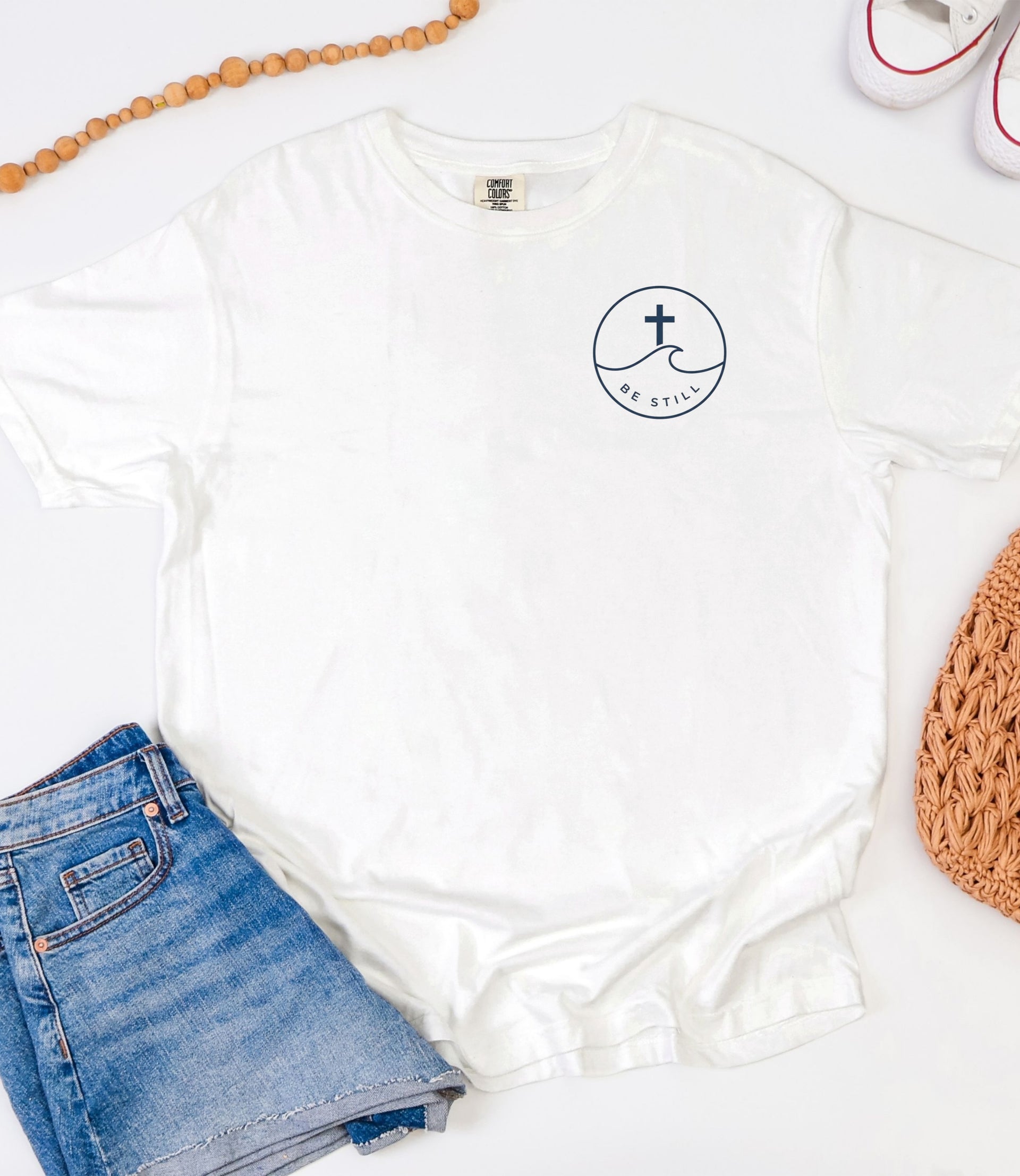 Peace Be Still T Shirt displayed with denim shorts and casual accessories, emphasizing comfort and style.