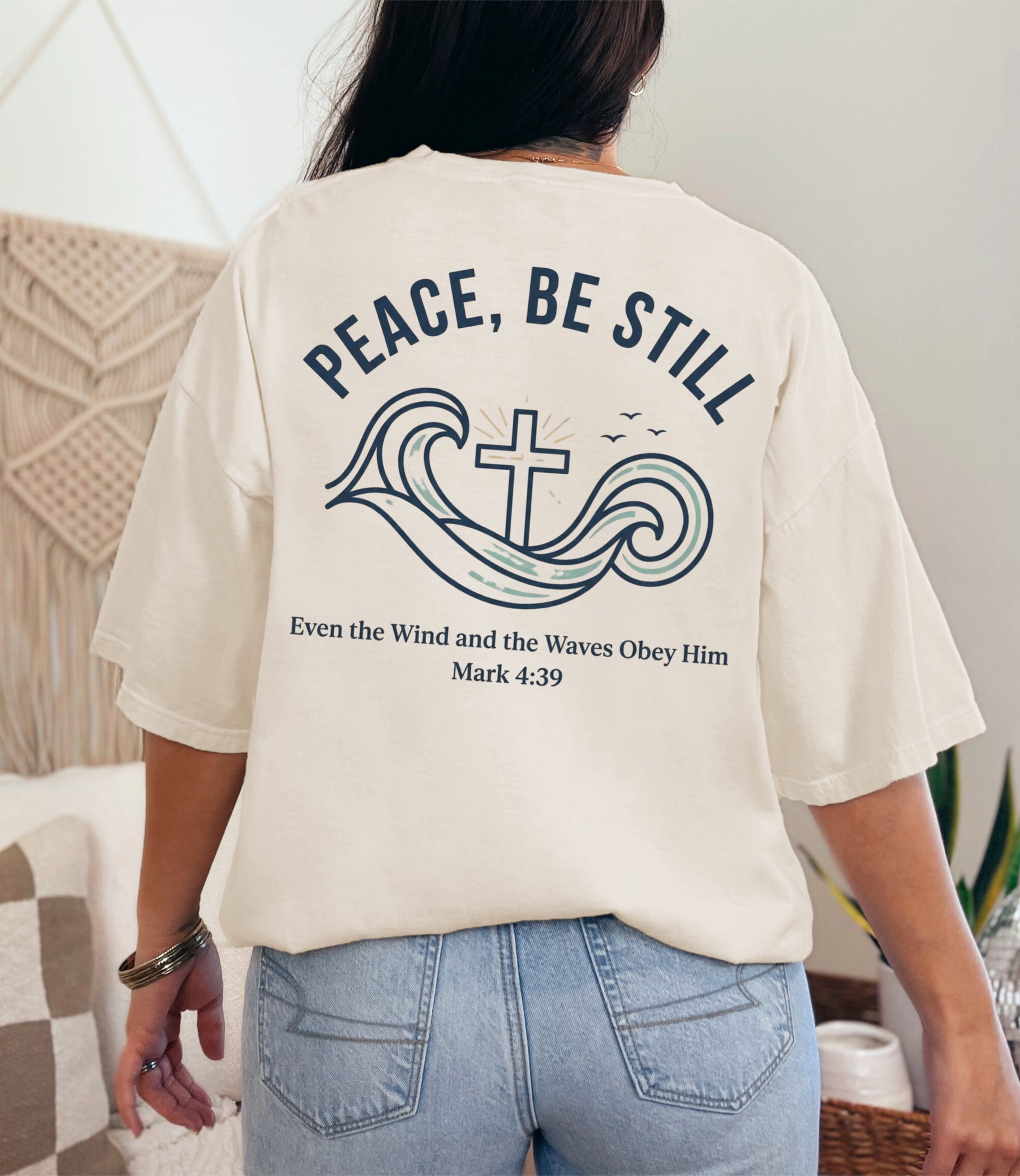 Peace Be Still T Shirt displayed on model, featuring calming wave and cross design with scripture Mark 4:39.