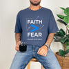 Man wearing a navy Faith > Fear T shirt, holding a mug, promoting faith over fear t shirt message.