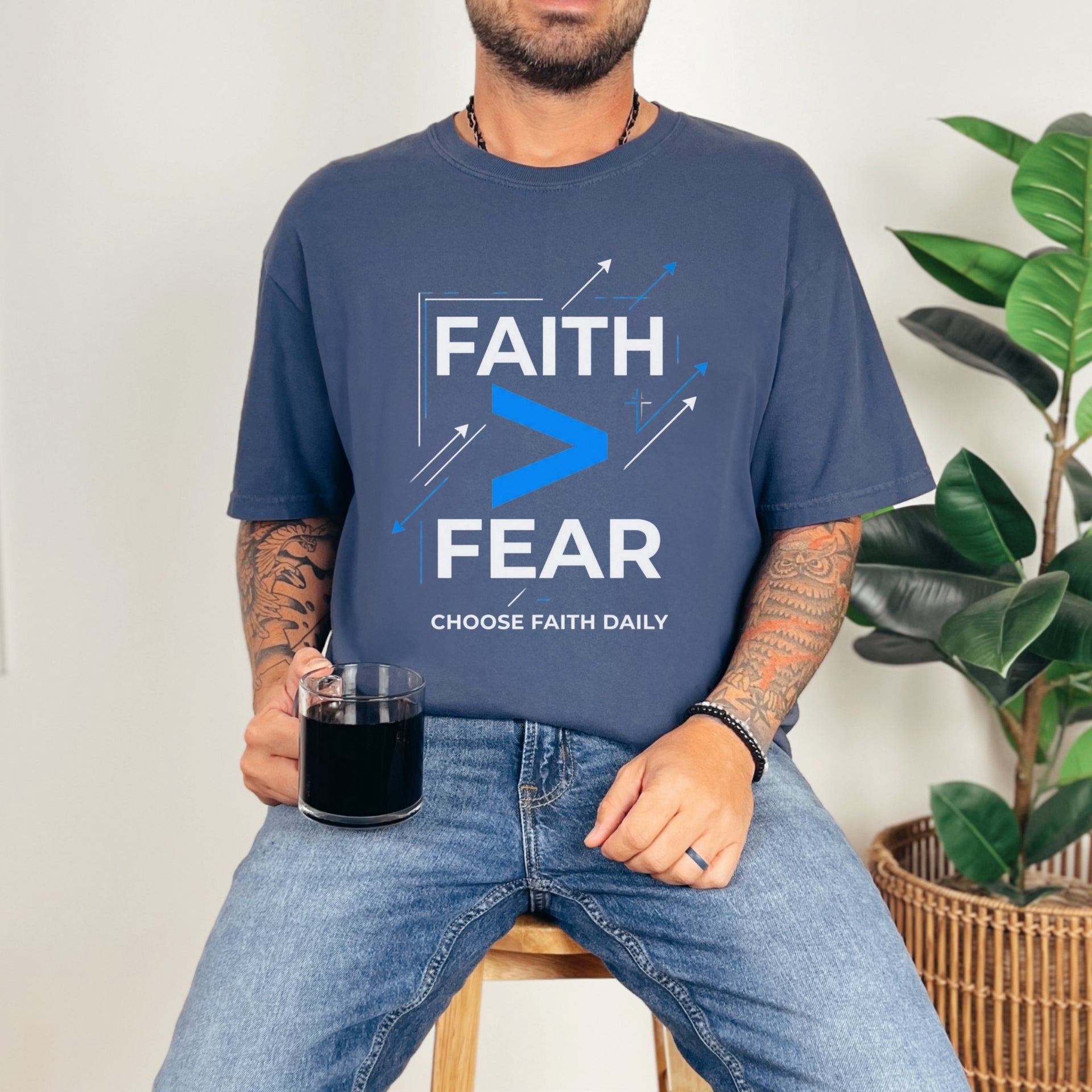 Man wearing a navy Faith > Fear T shirt, holding a mug, promoting faith over fear t shirt message.