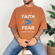 Man wearing Faith > Fear T shirt in rust color, promoting the message of faith over fear t shirt.