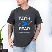 Man wearing a Faith > Fear T shirt promoting courage and trust with bold design and relaxed fit.