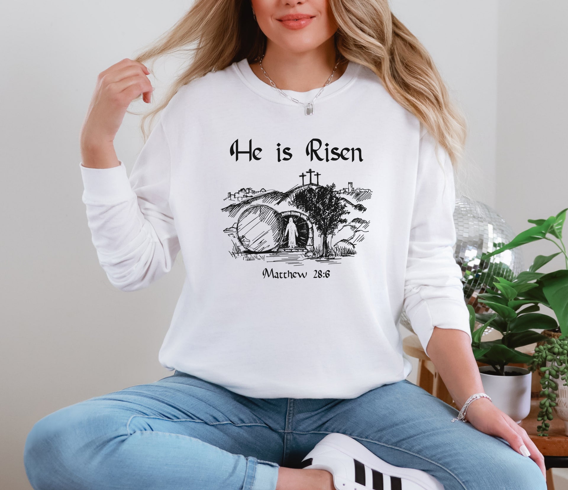He Is Risen long sleeve t-shirt featuring Matthew 28:6 design on a woman, symbolizing resurrection and hope.
