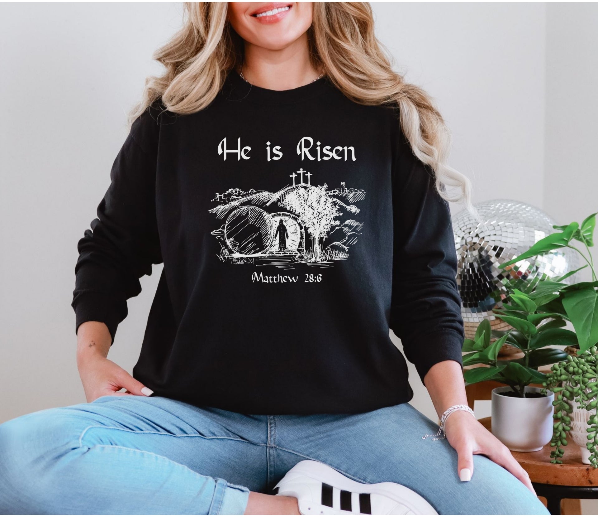 He Is Risen long sleeve t-shirt worn by a woman with a Christian design featuring Matthew 28:6.