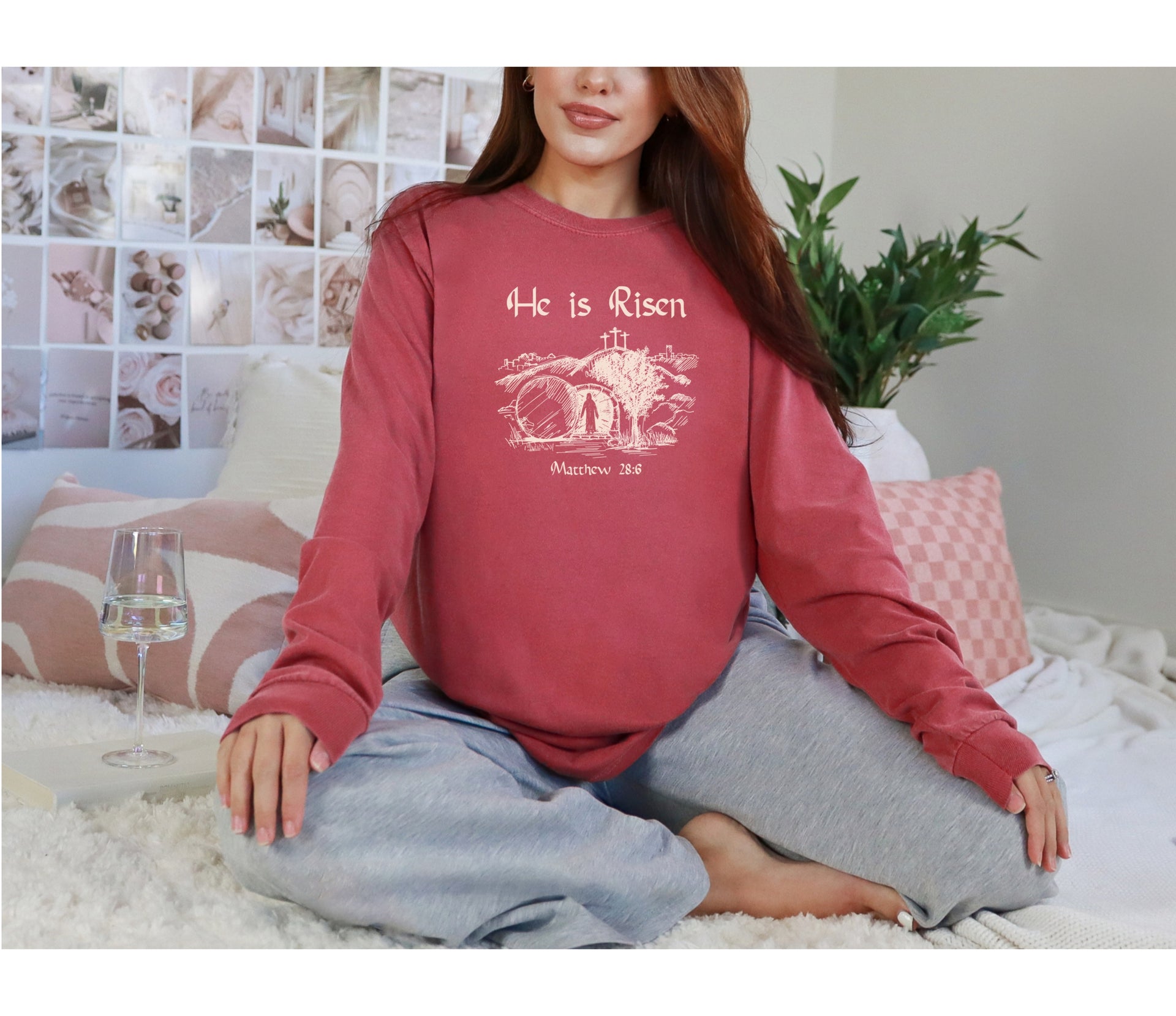 He Is Risen long sleeve t-shirt displayed on a woman sitting on a couch with a soft background.