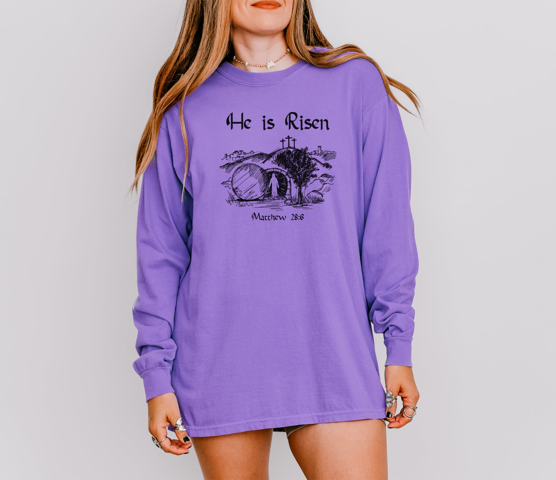 He Is Risen long sleeve t-shirt in purple featuring Matthew 28:6 print; a reminder of Christ's resurrection.