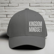 Flexfit Kingdom Mindset hat in grey with white embroidery against a brick background.