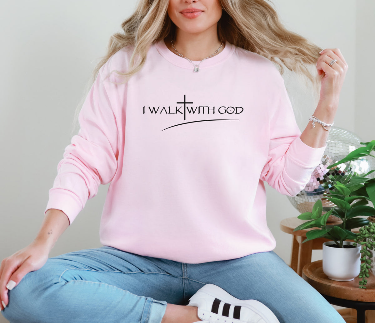 I Walk With God Long Sleeve T Shirt in pink worn by a woman sitting casually with a plant in the background.