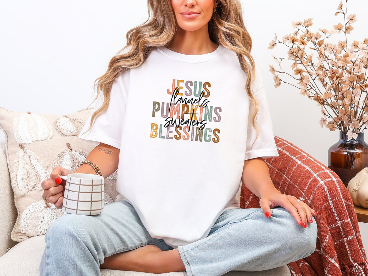 Woman wearing a white Christian autumn graphic t-shirt featuring Jesus Flannels Pumpkins Sweaters Blessings design while holding a mug.