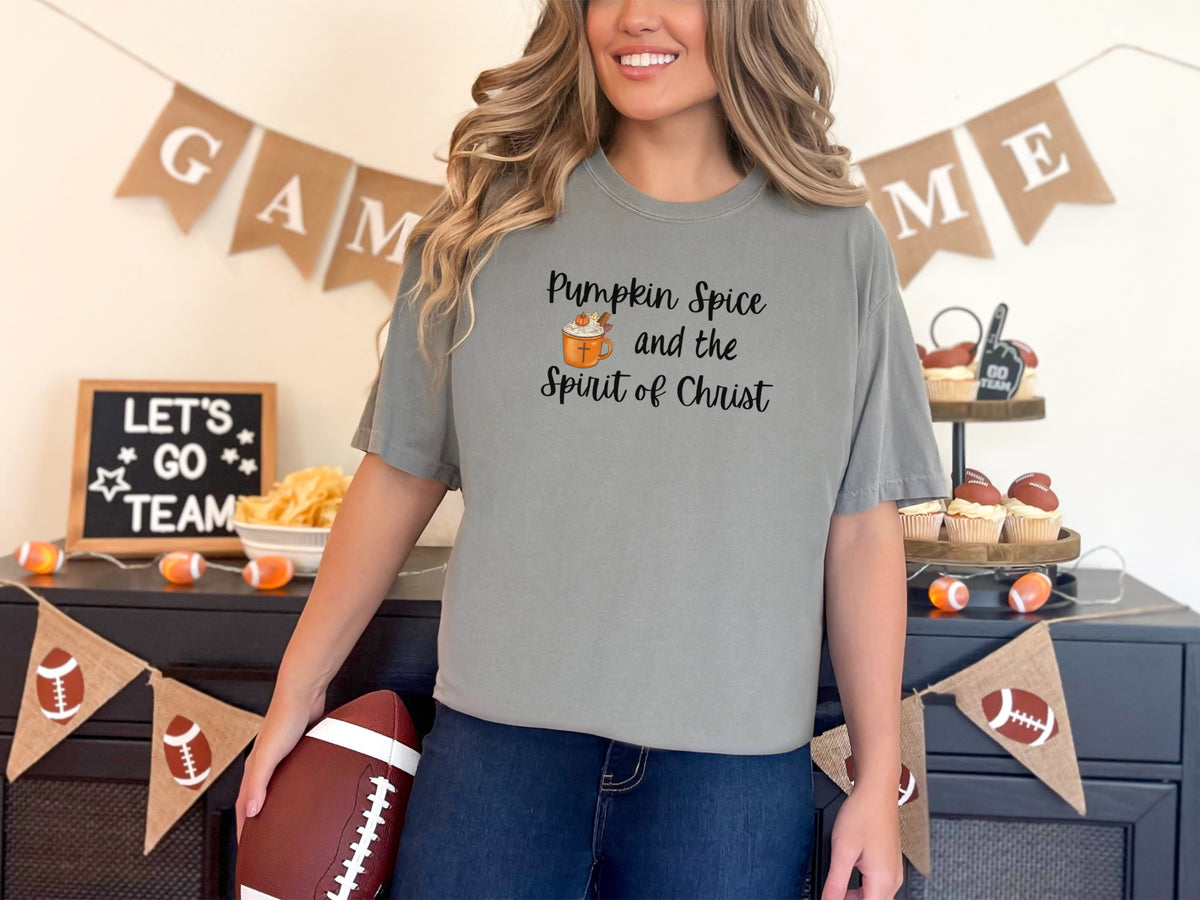 Grey pumpkin spice Christian t-shirt worn by a woman, featuring the phrase 'Pumpkin Spice and the Spirit of Christ'.