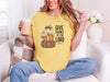 Woman wearing a mustard Give Thanks to the Lord t-shirt with pumpkin design while enjoying a drink.
