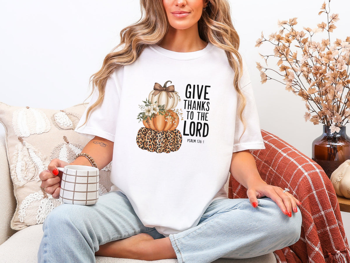 Woman wearing Give Thanks to the Lord t-shirt, featuring stacked pumpkins, celebrating gratitude and fall spirit.