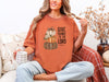Woman wearing Give Thanks to the Lord T-Shirt in Yam color, featuring pumpkin graphic, sipping coffee.