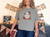 Jesus Fills My Cup t-shirt in grey worn by a model, featuring a cozy cup graphic and fall leaves.