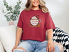 Woman wearing a Chili Jesus Fills My Cup t-shirt with graphic design and cozy background.