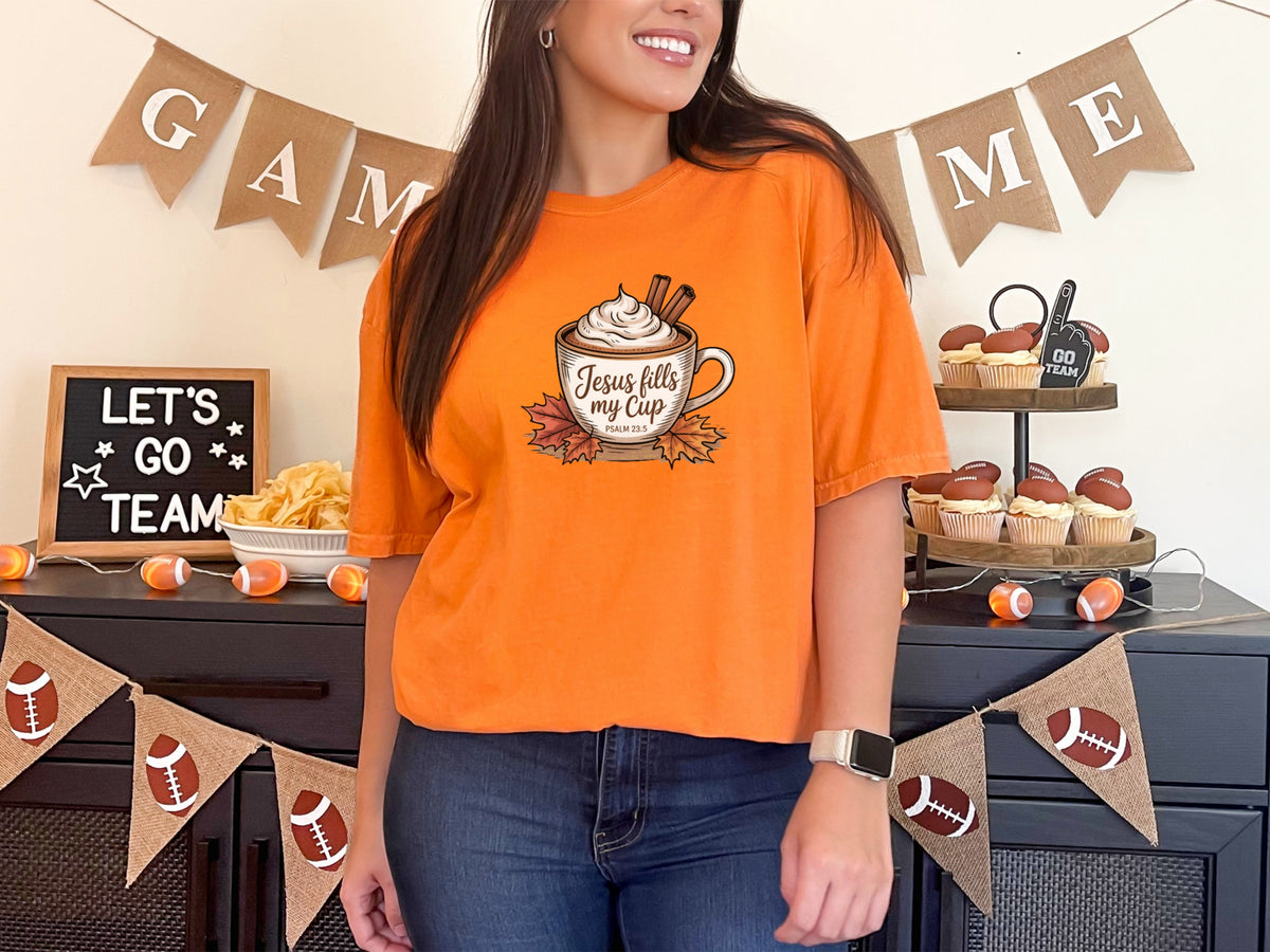 Jesus Fills My Cup t-shirt in burnt orange worn by a woman at a game-themed event.